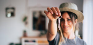 Une personne souriante tient dans sa main les clés de son logement