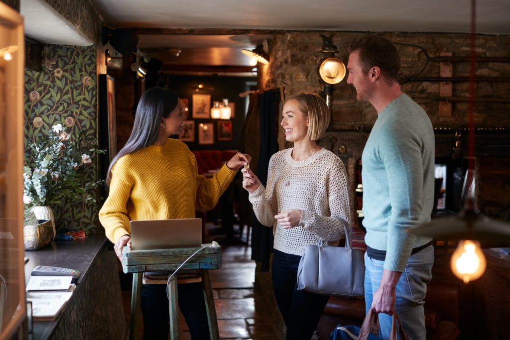 Réceptionniste donnant la clé d'un hébergement à un couple de visiteurs